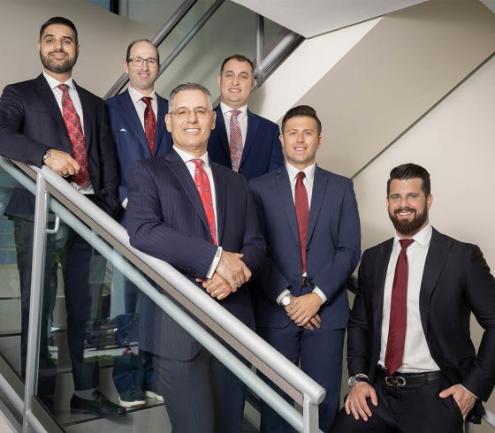 Six professionally dressed men posing on a staircase for a business portrait.